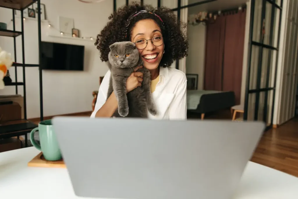 Frau hält ihre Katze vor ihren Laptop Wie Haustierbesitzer online zueinanderfinden