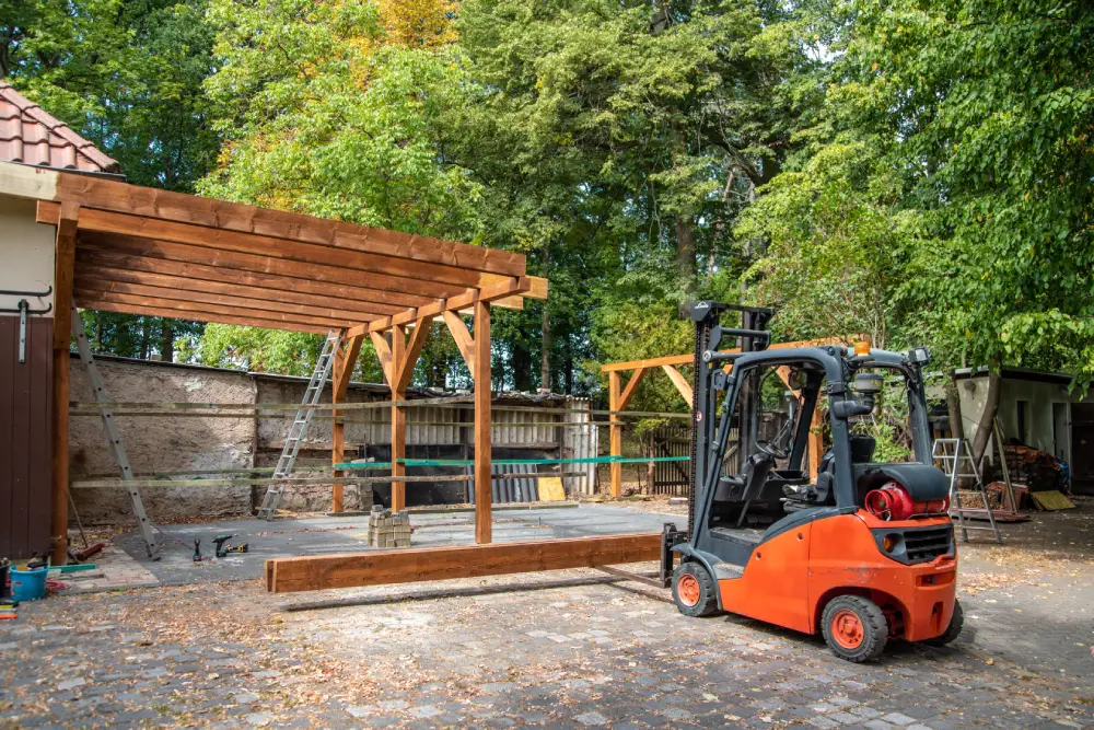 Robuste Dachbohlen für den Carportbau werden mit einem Stapler angehoben.