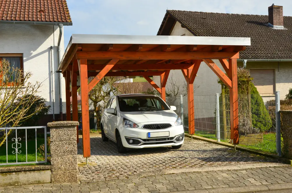 Freistehender Holzcarport mit Flachdach als Unterstand für ein Auto.